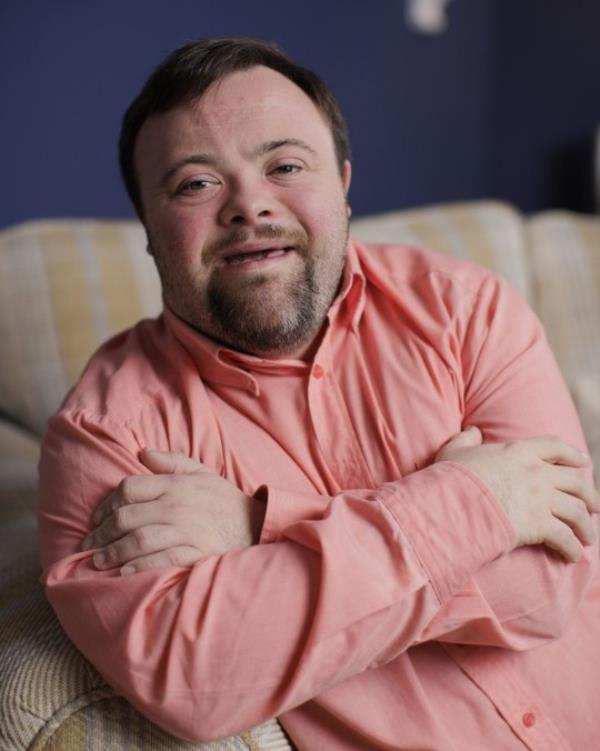 A photo of actor James Martin, wearing a salmon shirt, with a blue background.